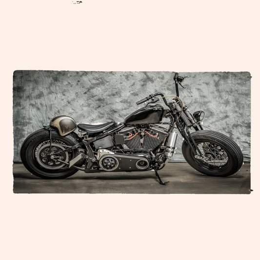 A vintage-style motorcycle with black and chrome components, positioned indoors against a textured grey background, likely used for product photography of the beach towel with a motorcycle pattern.