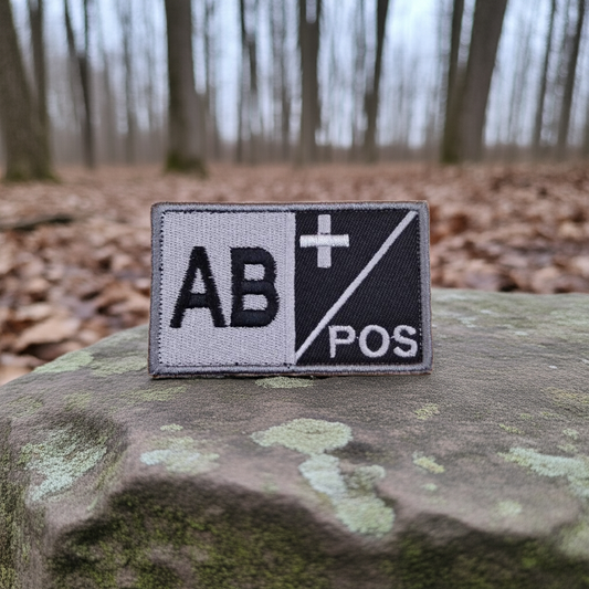 AB POS blood type patch on a textured surface with a forest background