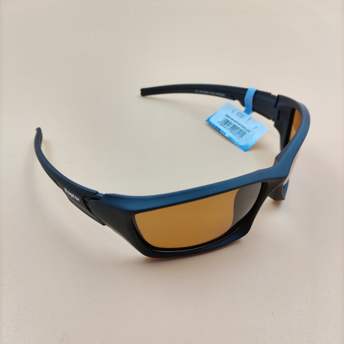 A pair of Raptor Sunglasses with polarized lenses lying flat against a beige surface.