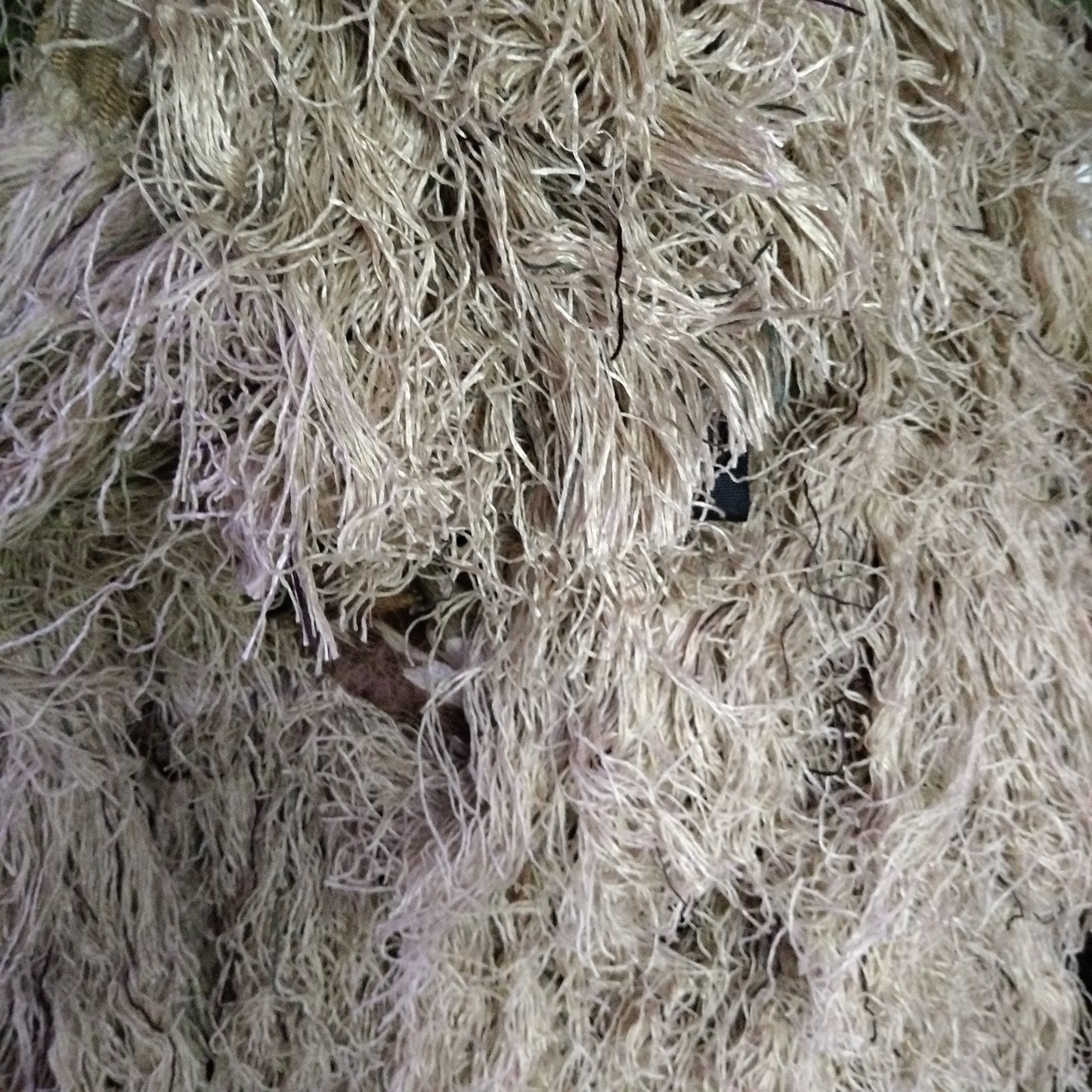 Brown ghillie suits in a natural outdoor setting, the suits appear to be made of natural camouflage material.