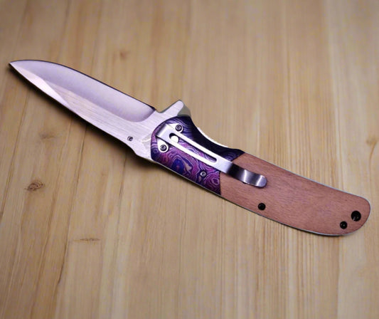 Folding knife with purple handle on a wooden surface