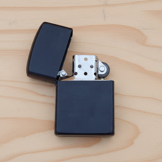 A black lighter with the cap removed, displayed on a beige background.