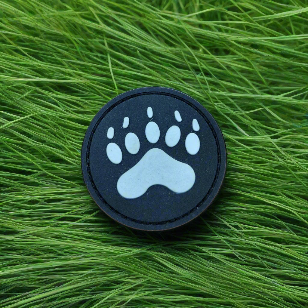 Round black patch with a white paw print on green grass