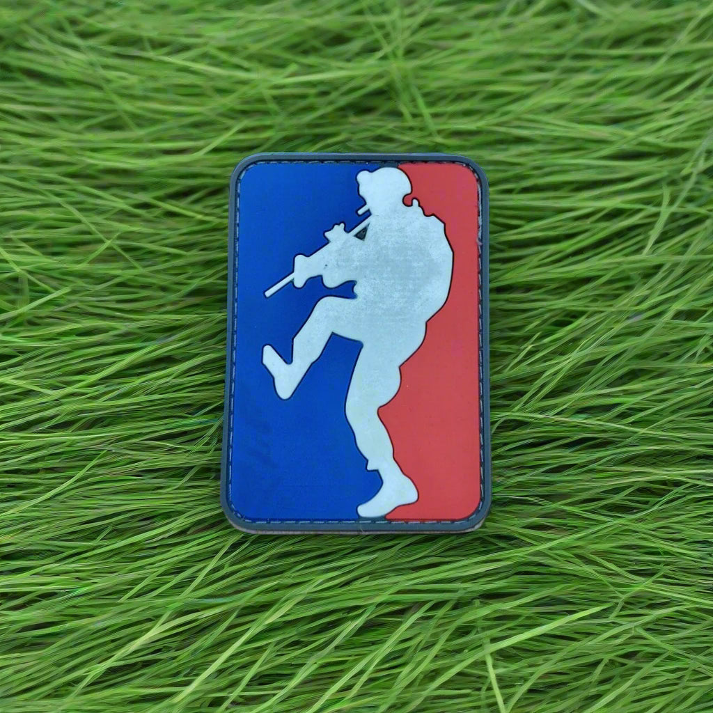 Logo patch with a silhouette of a person holding a rifle on a grass background