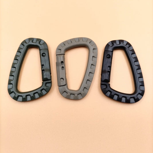 Three carabiner D rings in black, khaki, and green colors placed on a beige background.