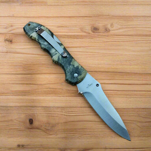 Folding knife with camouflage handle on a beige background