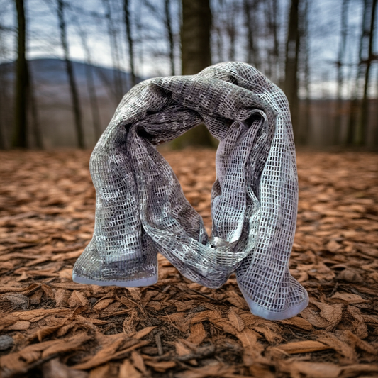 Textured scarf on a forest floor with trees and mountains in the background