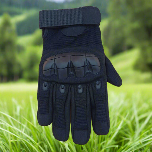 Black tactical glove on a blurred green outdoor background