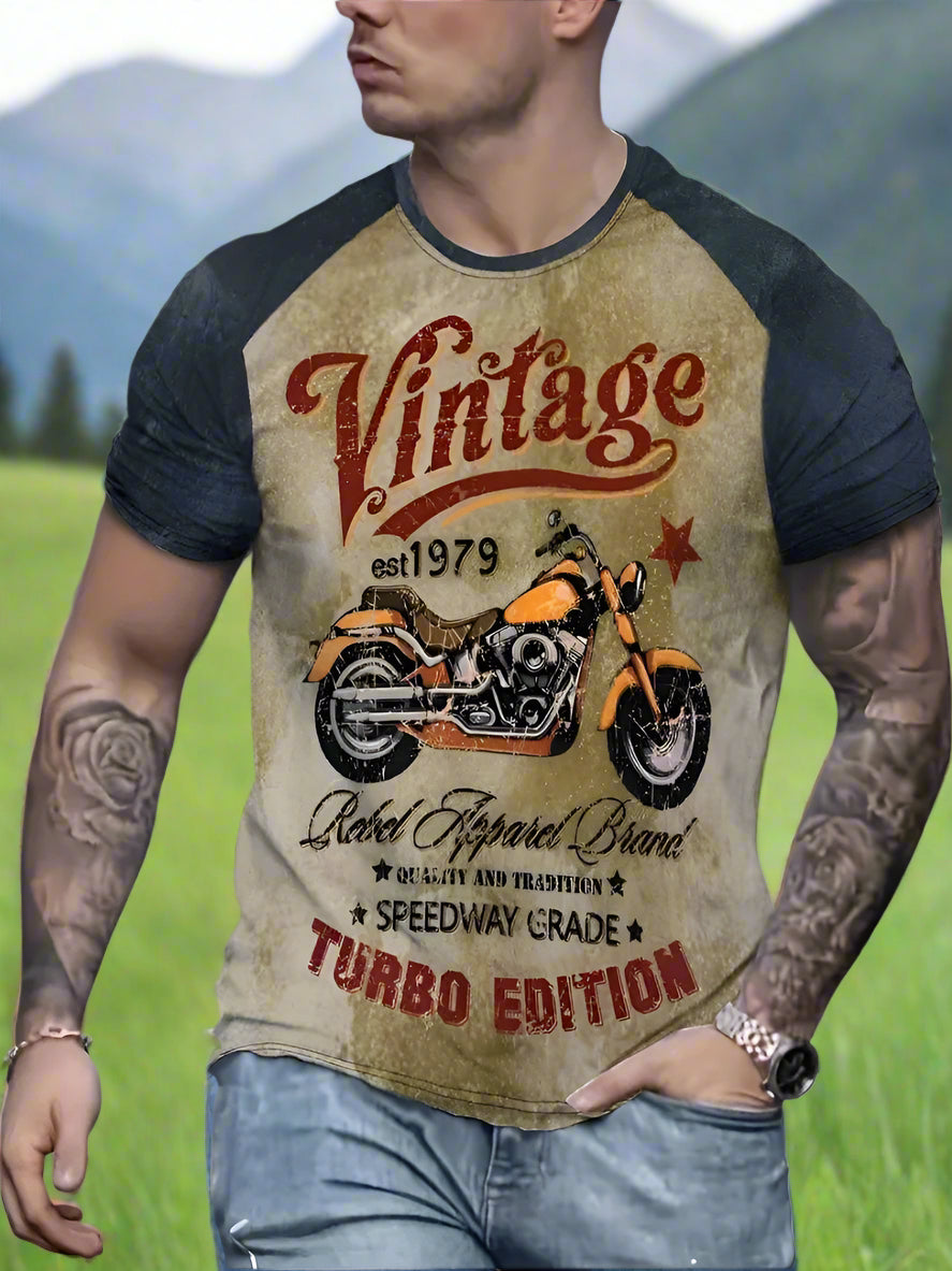 A male model wearing a short-sleeved vintage graphic t-shirt with a motorcycle design and text on the front.