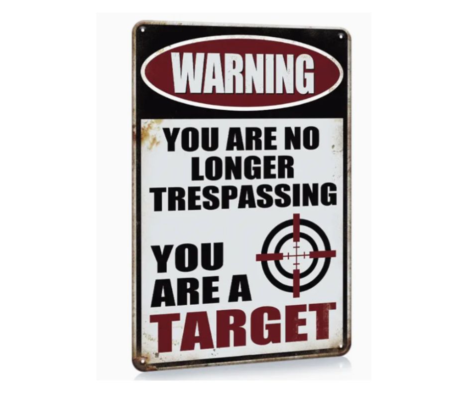 Warning sign on a wooden fence with text and a target symbol.