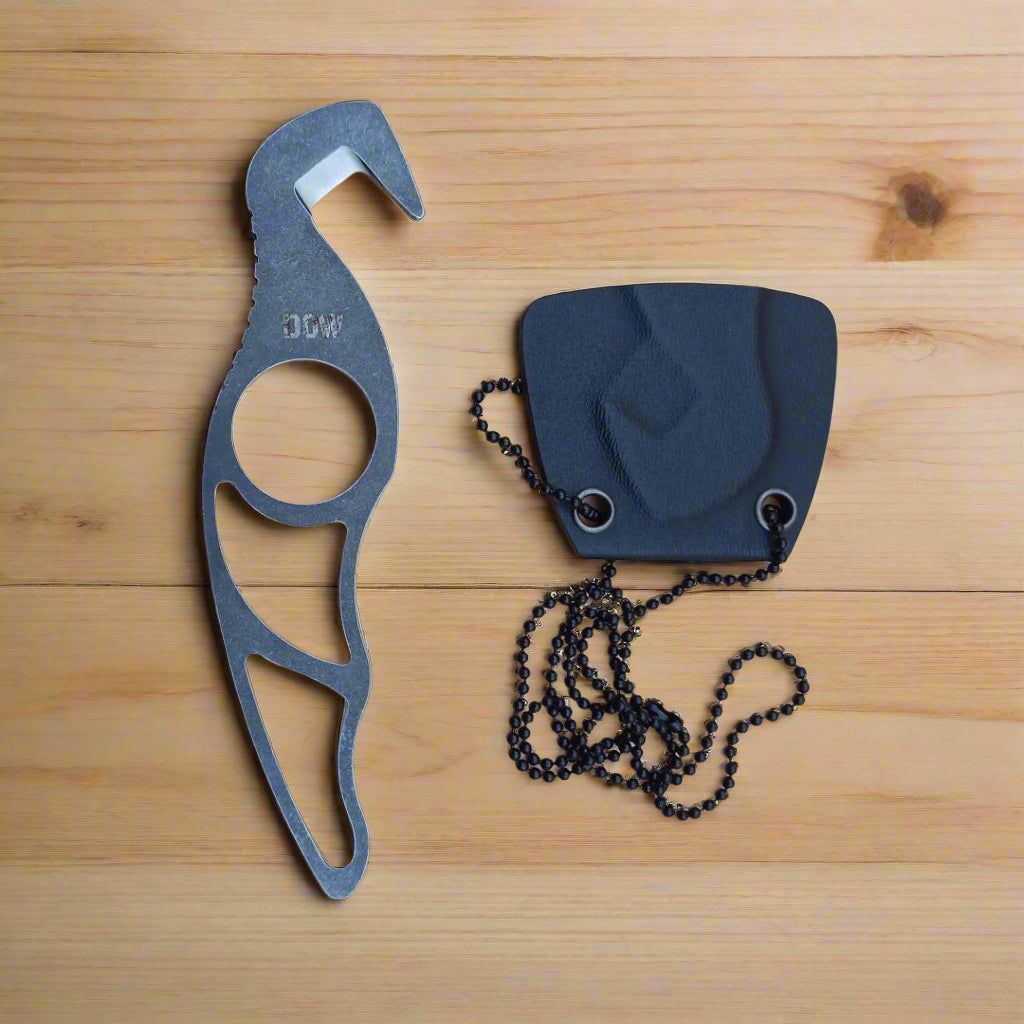 A neck knife with a gray handle and a black sheath, placed on a beige surface.