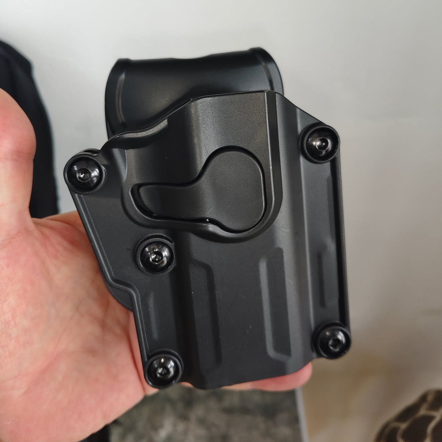 Black holster held by a person against a neutral background
