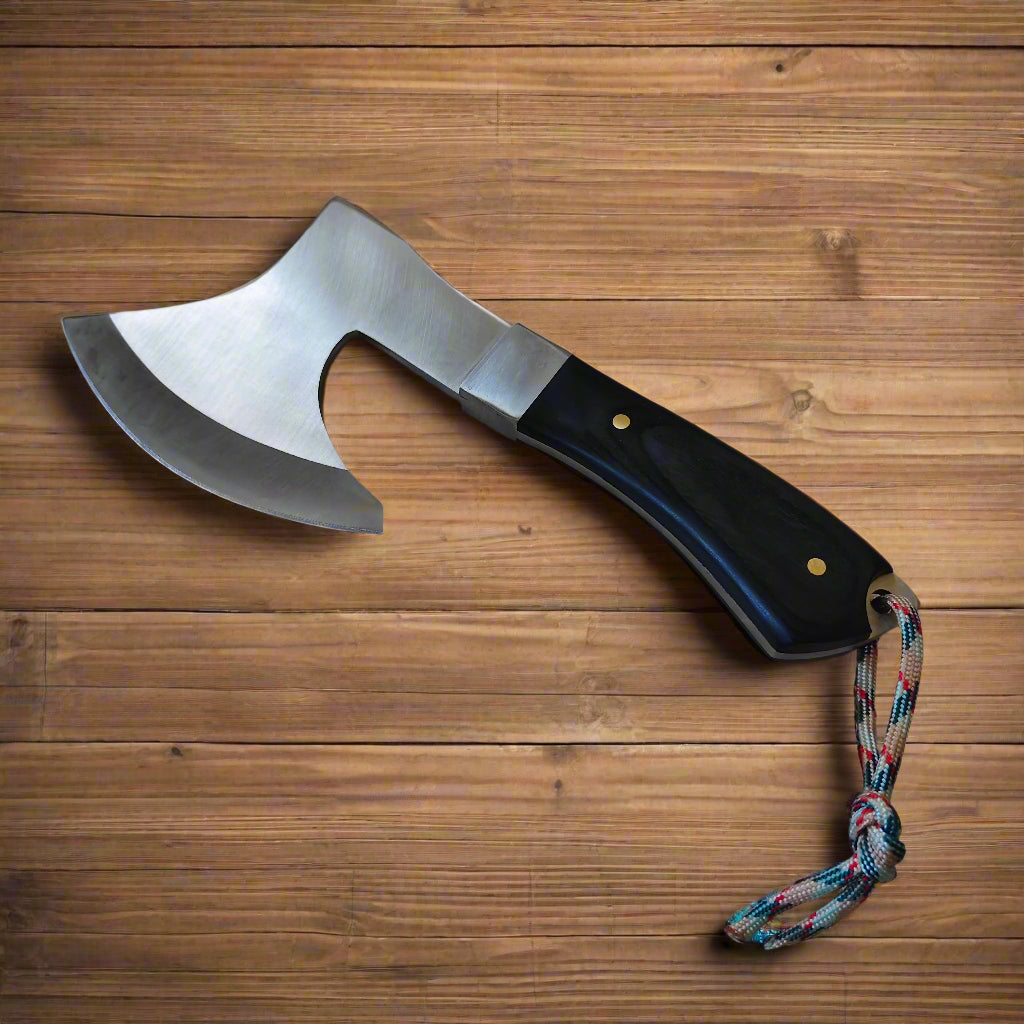 Small axe with a black handle and colorful cord on a beige surface