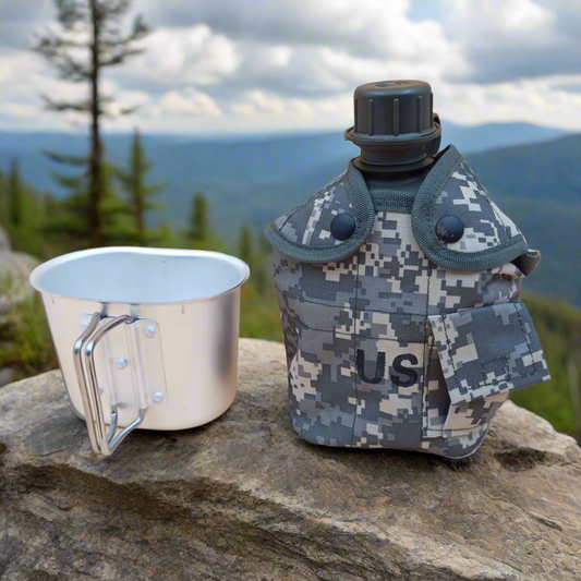 Camouflage canteen with US marking and metal cup on a rock with a mountainous background
