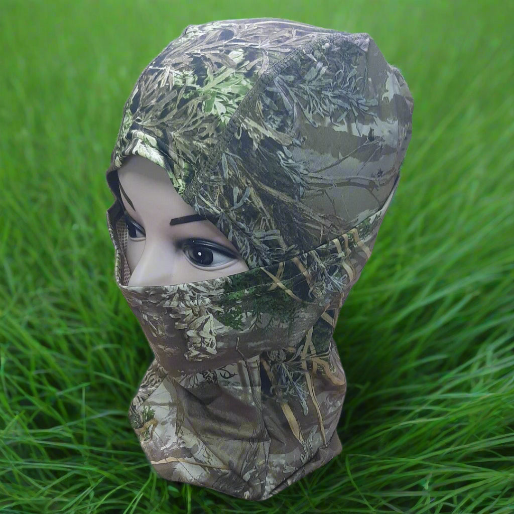 Camouflage hood on a mannequin head against a grassy background