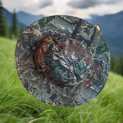 Camo-patterned hat on grass with mountains in the background