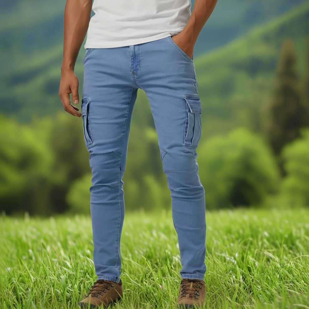 A person standing, wearing blue slim fit stretchable jeans with six pockets and white sneakers.