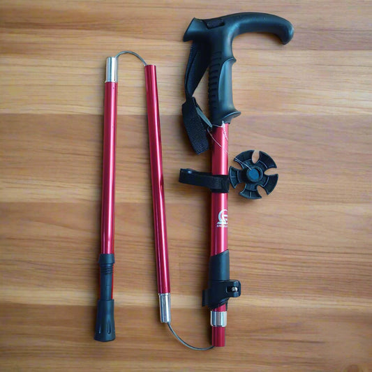 A foldable hiking stick in red color with black accents, displayed in both fully extended and folded positions alongside its components.