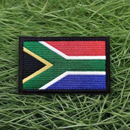 A patch with the South African flag, featuring a velcro back, displayed against a neutral background.