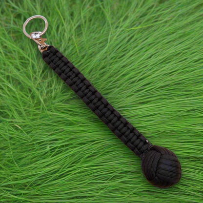 Three keychains with monkey fist design, in green, black, and brown colors, each with a steel ball at the end and a keyring.