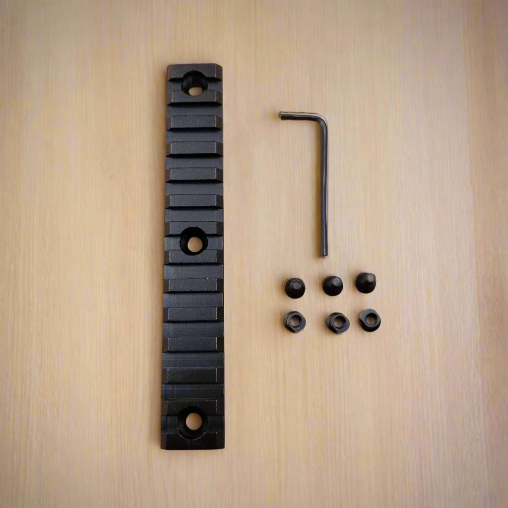 A set of three black aluminum Picatinny rails of varying sizes along with screws and an Allen key, arranged on a beige background.