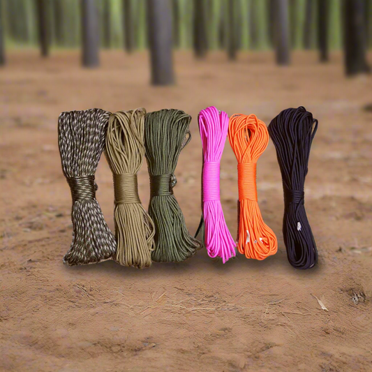 Five spools of colorful paracord on a forest floor.