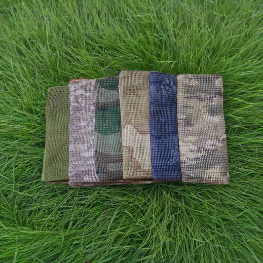 Five camouflage-patterned bags on a forest floor with trees in the background
