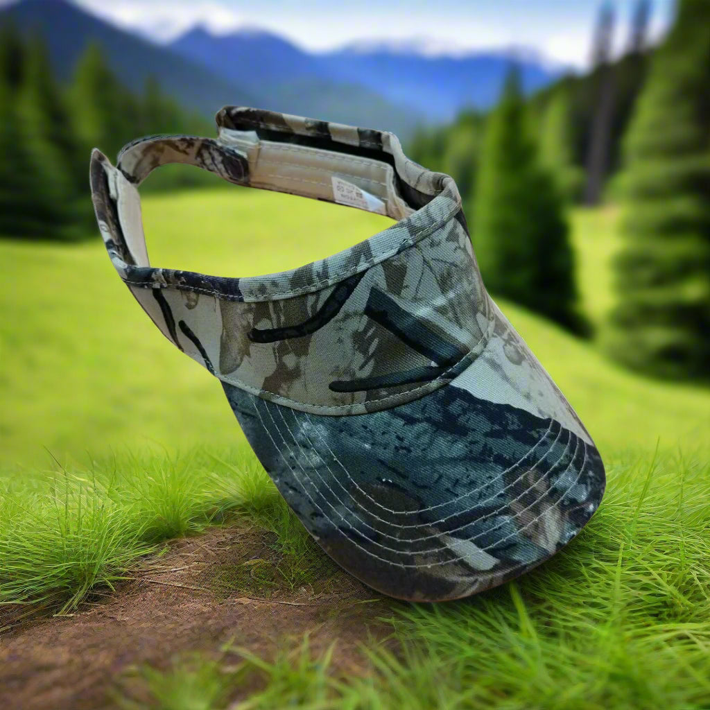 Camouflage visor on a grassy area with blurred greenery and mountains in the background