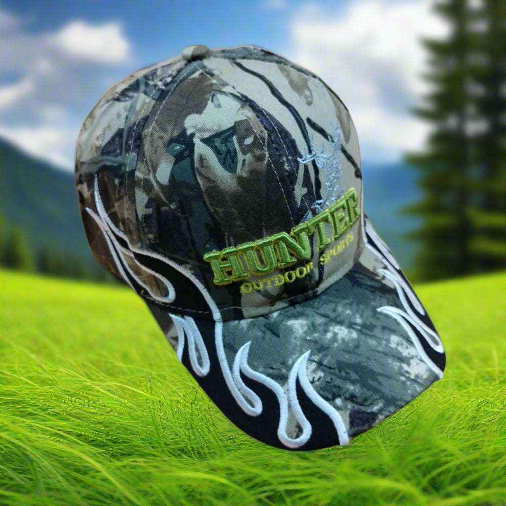 Camouflage cap with 'HUNTER' branding on grass with trees and sky in the background