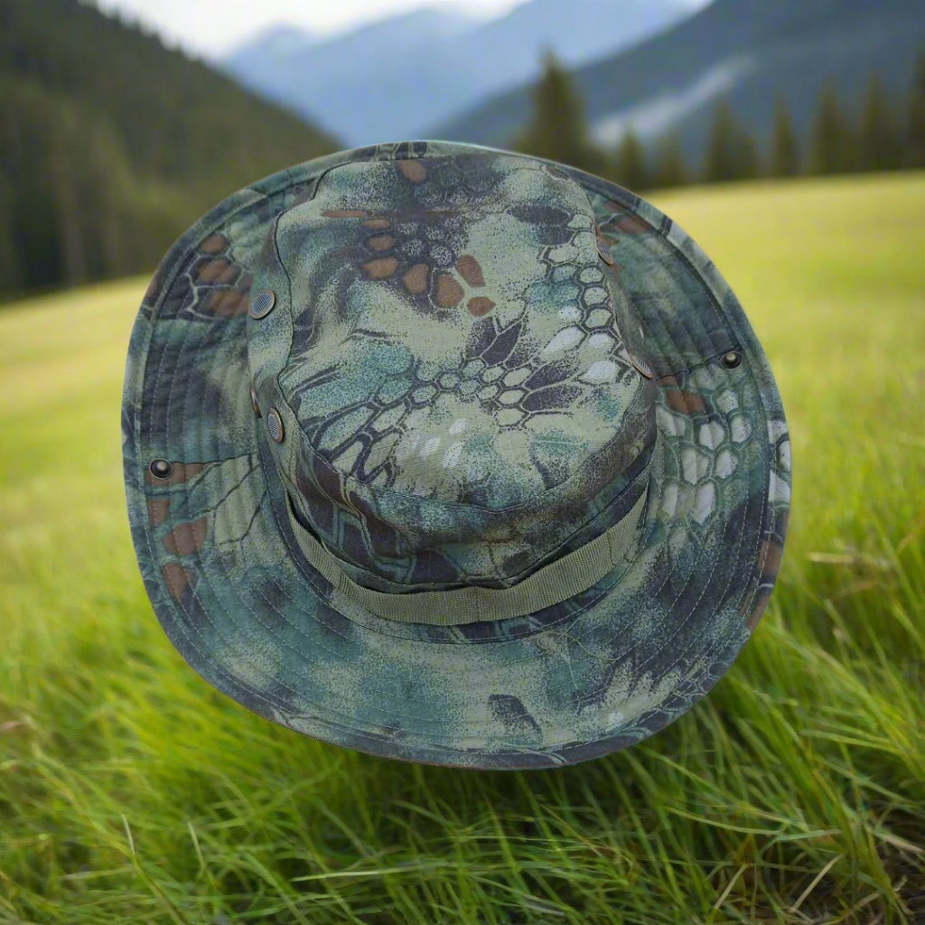 Camouflage-patterned hat on grass with mountains in the background
