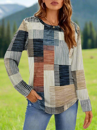 A woman wearing a long sleeve crew neck t-shirt with a geometric patchwork print in blue and khaki colors.