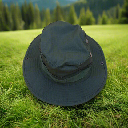 Green bucket hat on green grass with a forest background