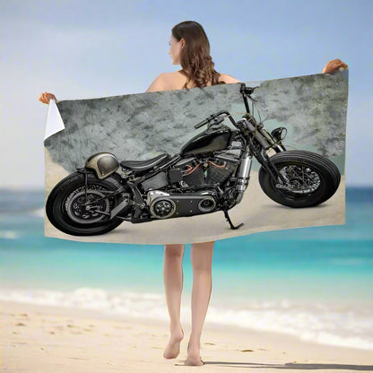 Woman holding a towel with a motorcycle design on a beach