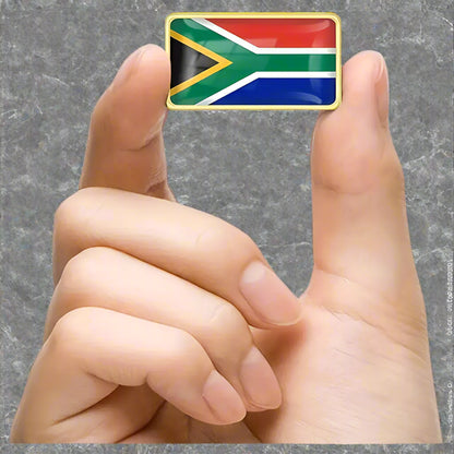 A pin shaped like the South African flag being held by a hand.
