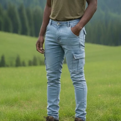 Person wearing light blue 6 pocket jeans pants and brown boots standing in a grassy field with trees in the background