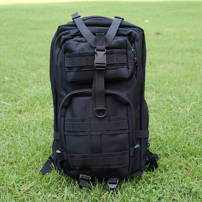 Black tactical backpack on a light gray surface with a wooden background