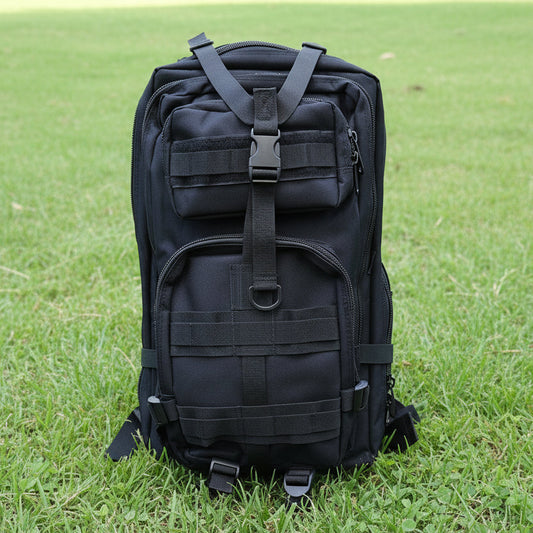 Black tactical backpack on a light gray surface with a wooden background