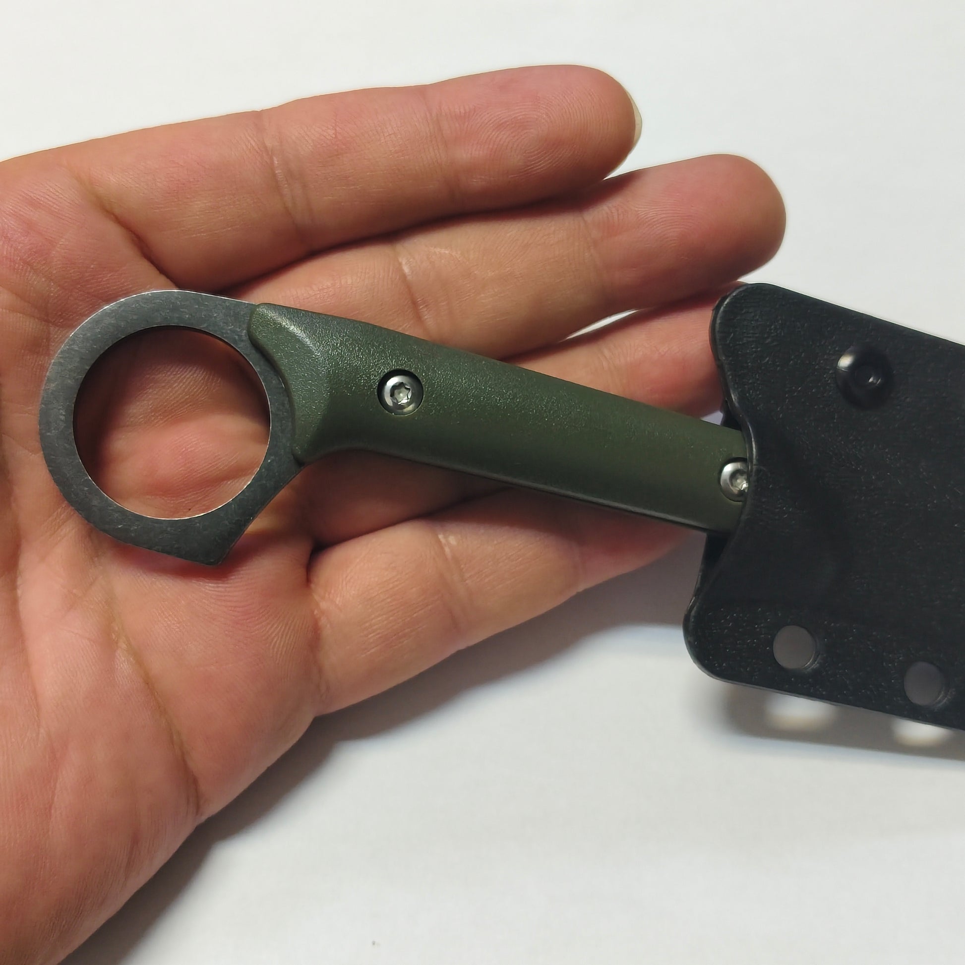 Hand holding a green folding knife with a sheath on a white background