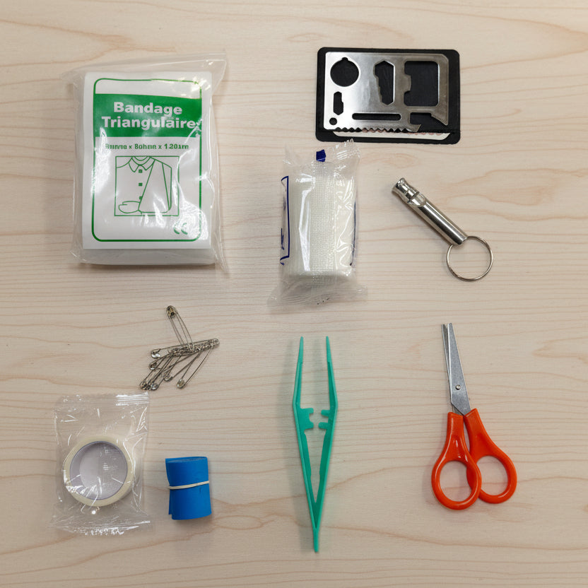 Collection of medical and utility items including bandages, scissors, and a multitool on a white background.