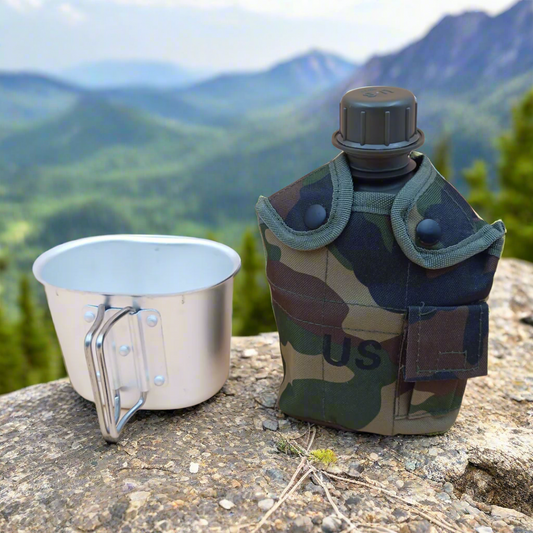 Camouflage canteen and metal cup on a rock with a mountainous background