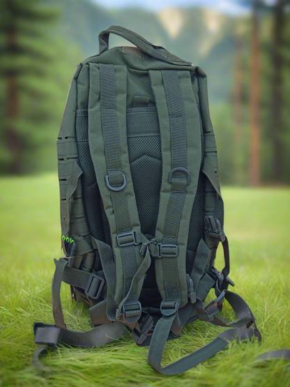 Green backpack on grass with blurred trees in the background