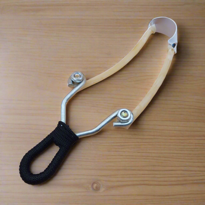 A slingshot with a metal frame and a black grip on a beige background.