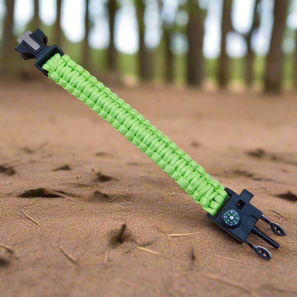 Green paracord bracelet with black clasp on a sandy background