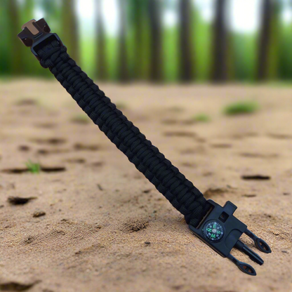 Black multi-tool bracelet with compass on a sandy background